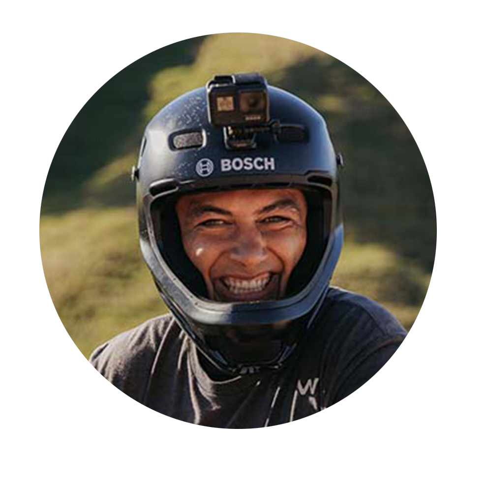 A smiling man is wearing a black Bosch helmet with a camera.