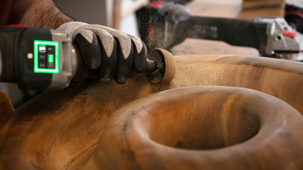 A craftsman is working with wood using a Bosch Professional tool.