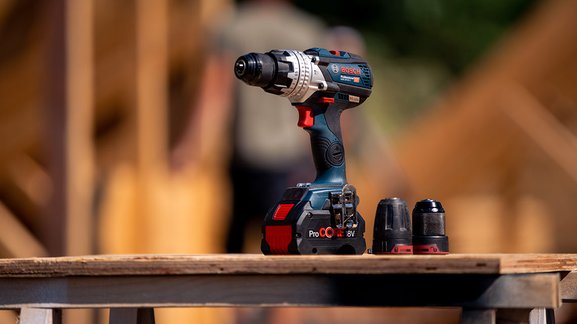 A Bosch Professional cordless drill stands on a stack of wood.