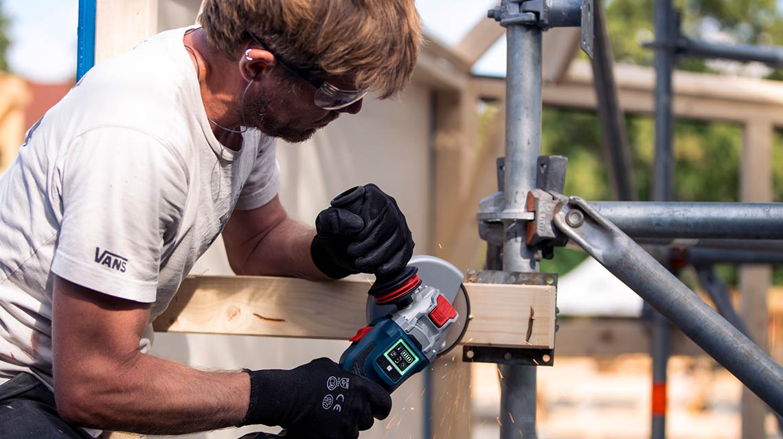 A craftsman is cutting wood with a Bosch tool at a construction site.