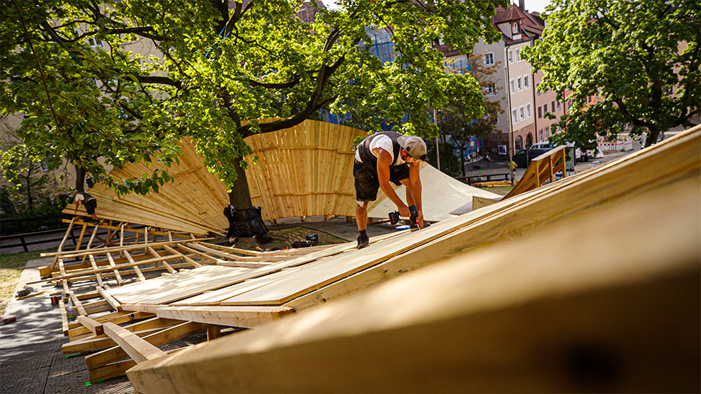 A craftsman is installing wooden panels on a curved structure.