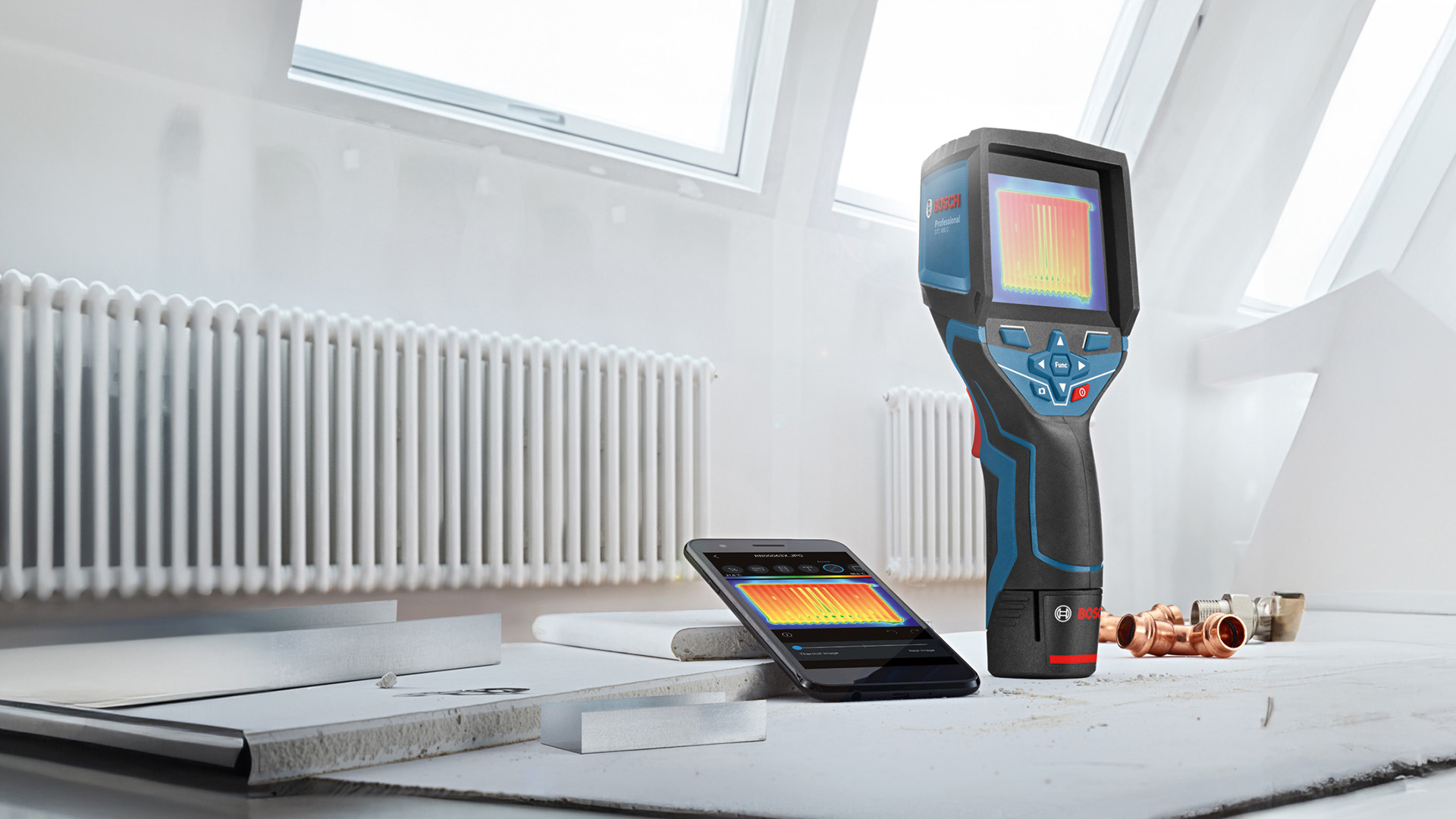 A Bosch Professional thermal imaging device is on a table next to a smartphone.