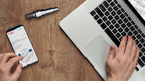 A smartphone and a laptop are on a wooden table, with tools beside them.